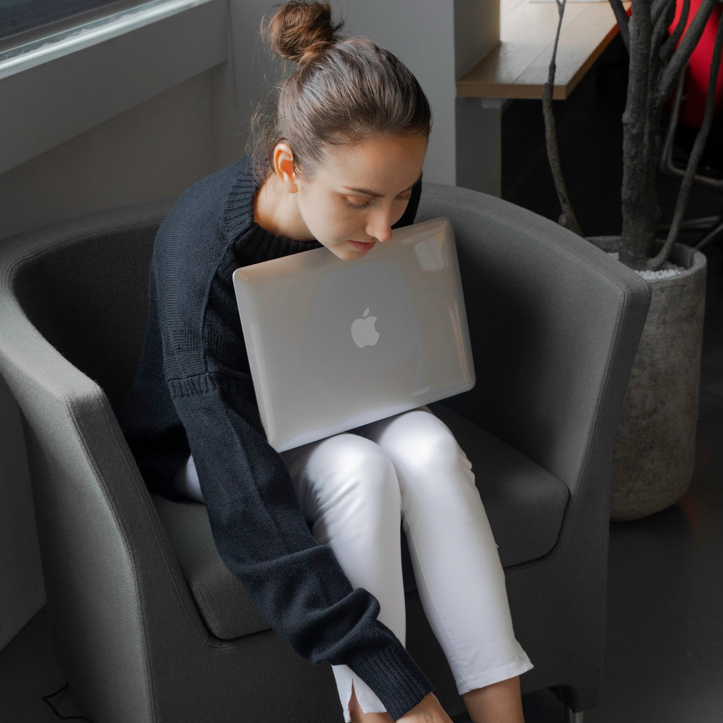 Woman relaxing on a gray chair with a laptop.